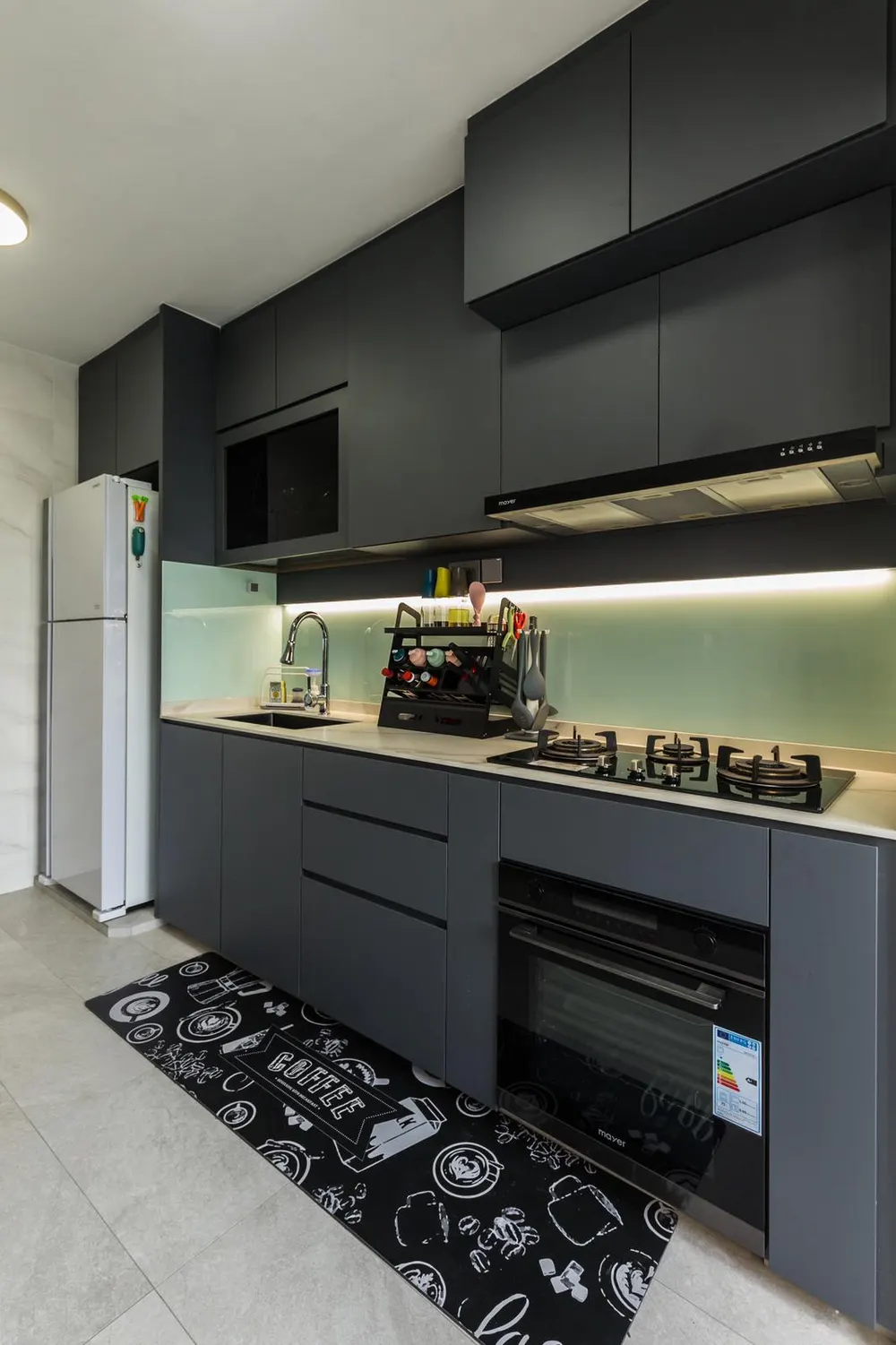A dark single-run HDB kitchen with a glass backsplash